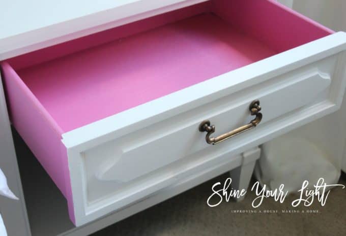 The inside of this thrifted bedside table is painted a fun hot pink.
